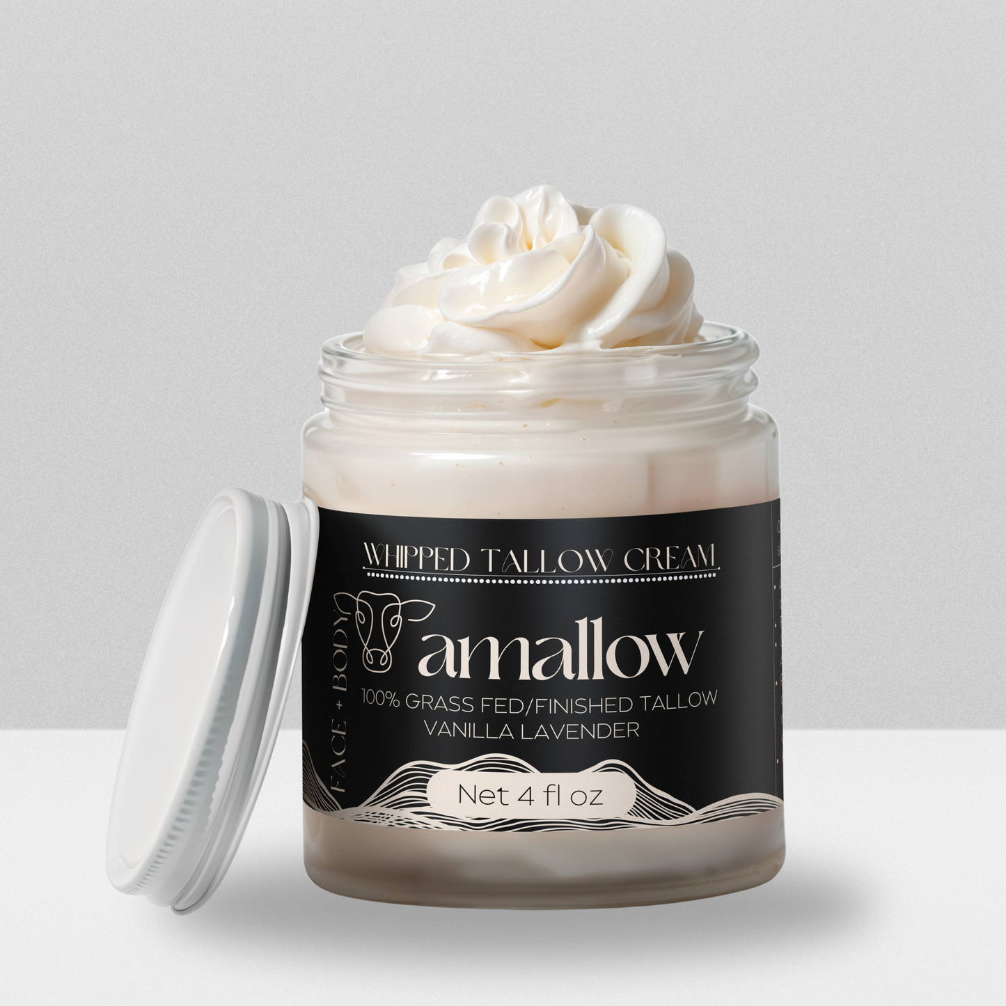 Vanilla Lavender product shown with cream coming out the top. Label is a black color. Whipped Tallow Cream 100% grass fed/finished. Net 4 Fluid Oz. Face + Body.