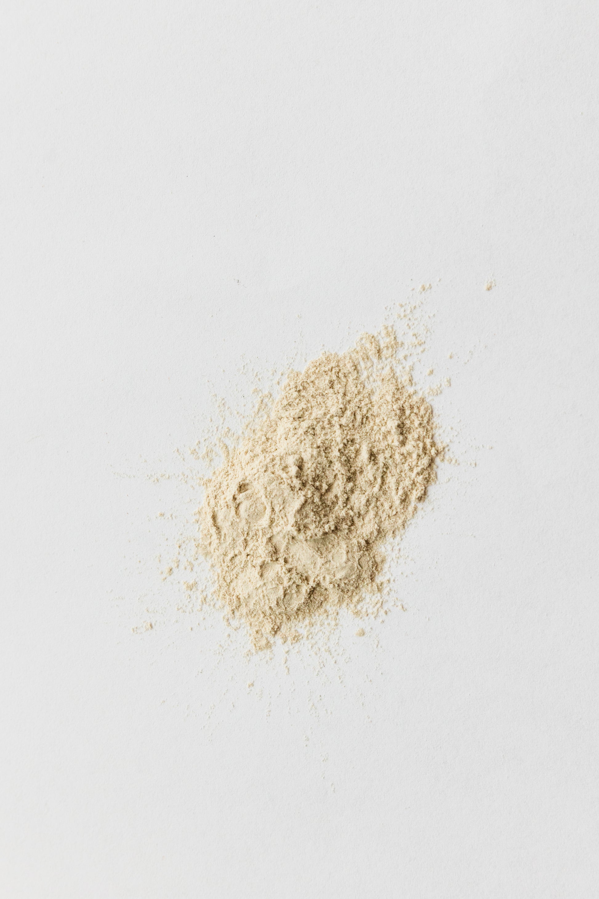 Picture of the dry shampoo powder on a white surface. It is light tan in color.