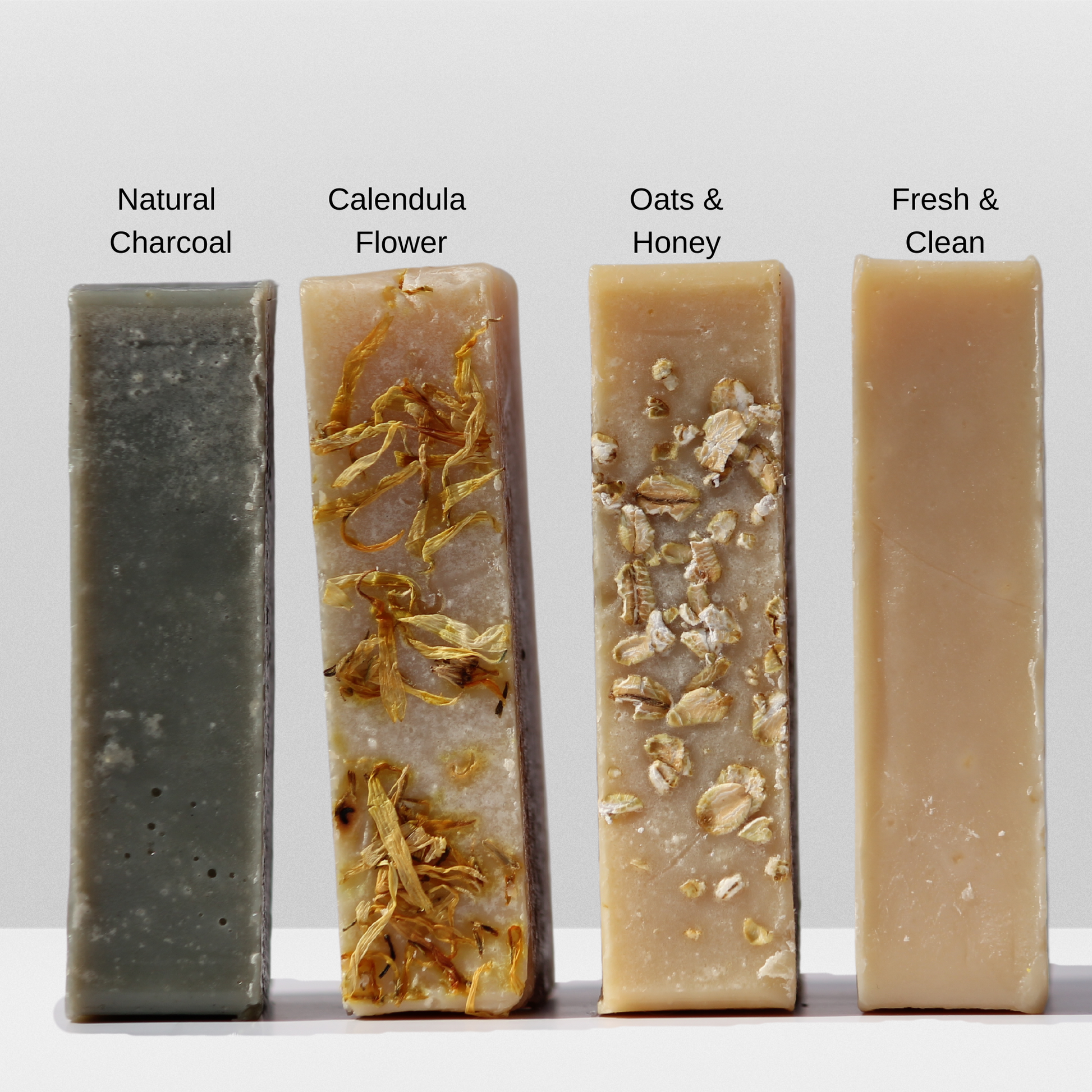 Picture showing all 4 goat milk soaps next to each other, natural charcoal, calendula flower, oats & honey, Fresh & Clean.