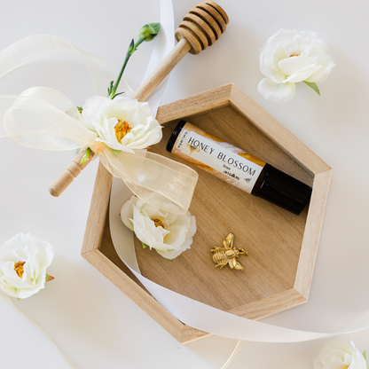 Photo shown of product in wooden hexagon with flowers, a gold bee decoration and a honey dipper. 