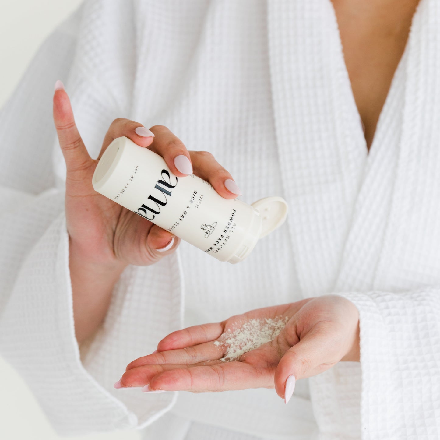 Woman applying powder facial cleanseer into hand.